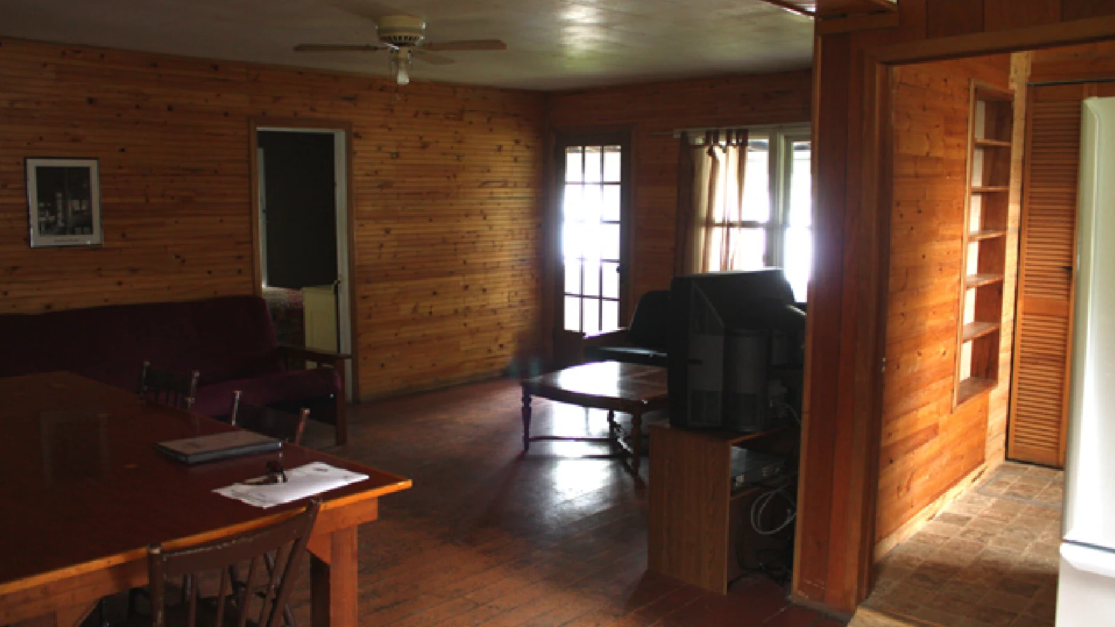Pigeon Lake Resort Cottage Two.&nbsp; Dining area with table and chairs connected to a kitchen in a wood-paneled cottage interior.